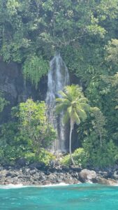 Waterfall on the coast next to rocky shore, rainforest meets ocean